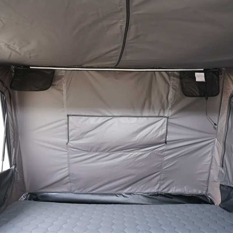 Gray interior of a tent with quilted mattress and window