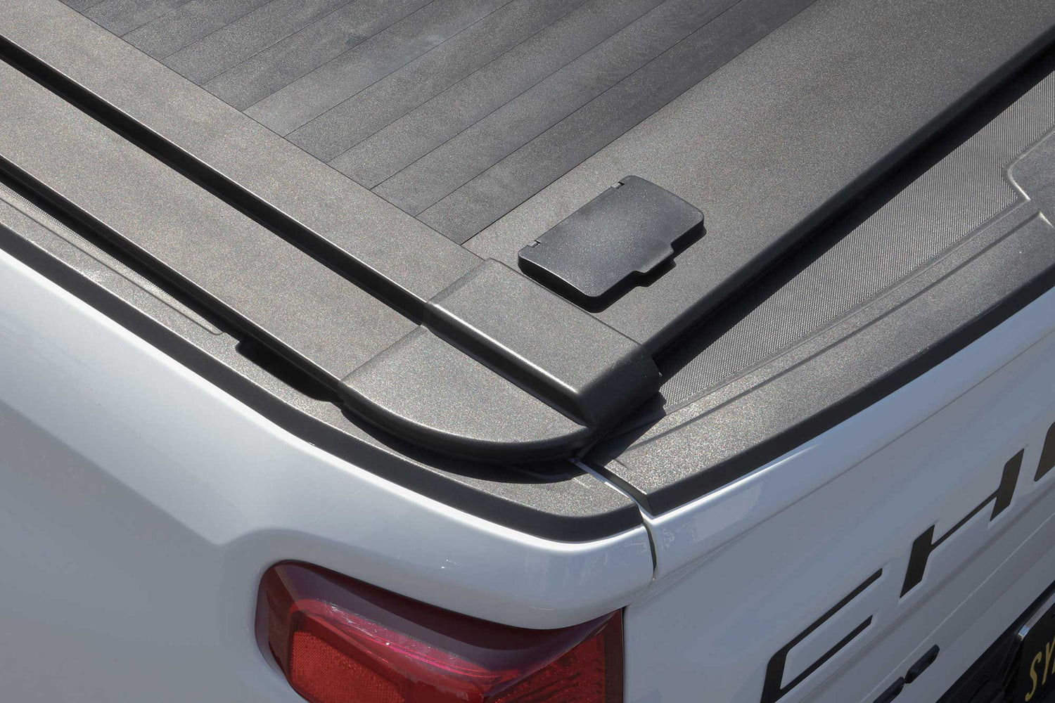 Close-up of a truck bed with enhanced MB retractable tonneau cover and Chevrolet logo.