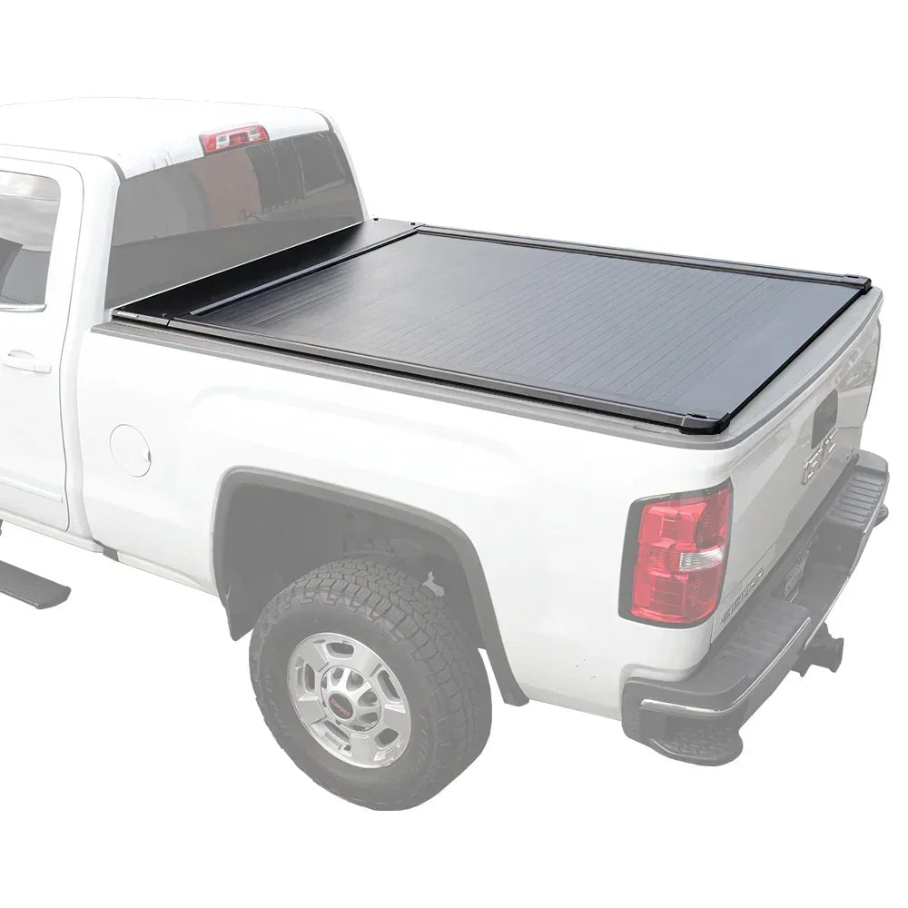 A retractable tonneau cover made of aluminum and plastic, installed on the bed of a white pickup truck.