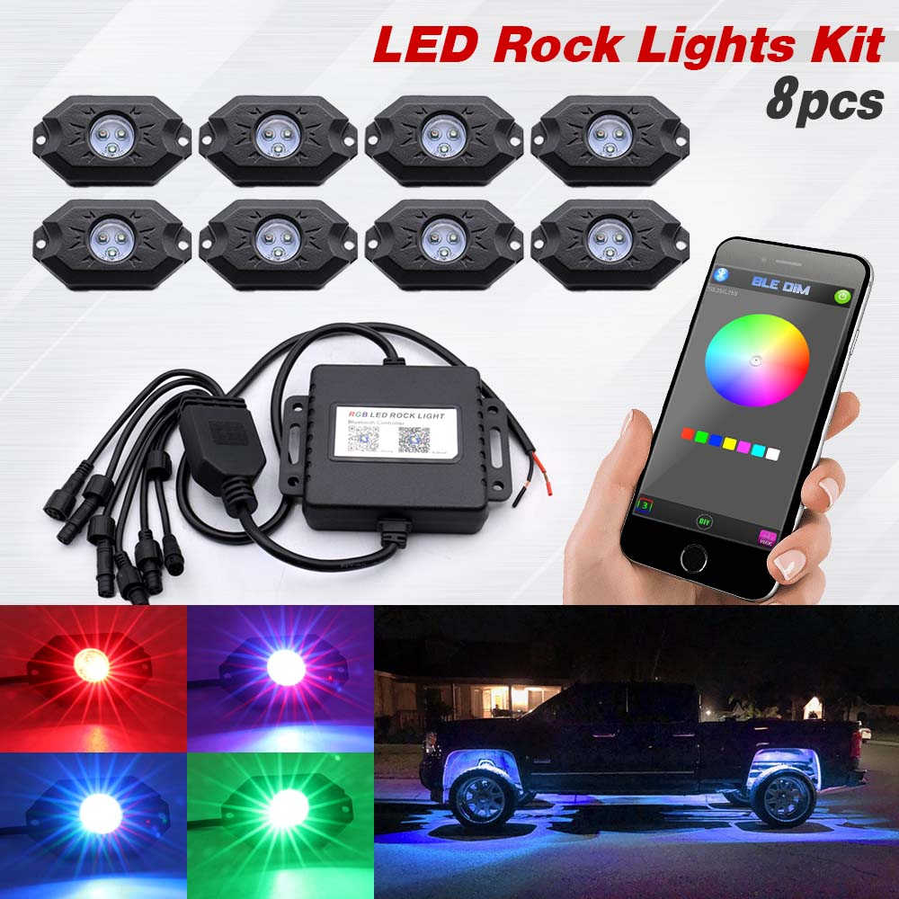 An 8-piece LED rock light kit shown on a white background, including eight black LED units, a black controller box with wiring, a smartphone displaying a color wheel app, and four inset images showing the lights glowing in red, blue, purple, and green. Text at the top reads 'LED Rock Lights Kit 8pcs'.