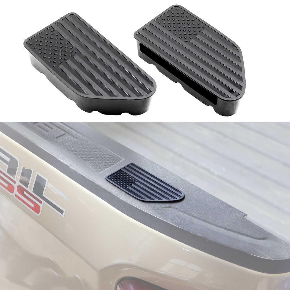 Two black rubber truck bed footrests with an American flag design, shown both as a pair on a white background and installed on the side of a beige pickup truck bed.