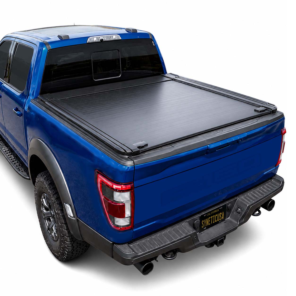A black tonneau cover for a pickup truck bed, shown installed on the tail of a blue pickup truck against a white studio background.