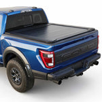A black tonneau cover installed on the bed of a blue Ford pickup truck, shown from a rear three-quarter angle against a clean white background.