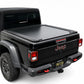 A black tonneau cover installed on the bed of a black Jeep Gladiator, shown from a rear three-quarter angle against a white studio background.