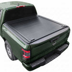 A black Frontier 6ft truck bed cover installed on the bed of a dark green pickup truck, shown from a rear three-quarter angle against a plain white background.