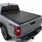 A black soft roll up tonneau cover installed on the bed of a silver Nissan Frontier 4x4 pickup truck, shown from a rear three-quarter angle against a white studio background.