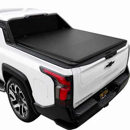 A black tonneau cover installed over the bed of a white Silverado EV truck, shown from a rear three-quarter angle against a plain white background.