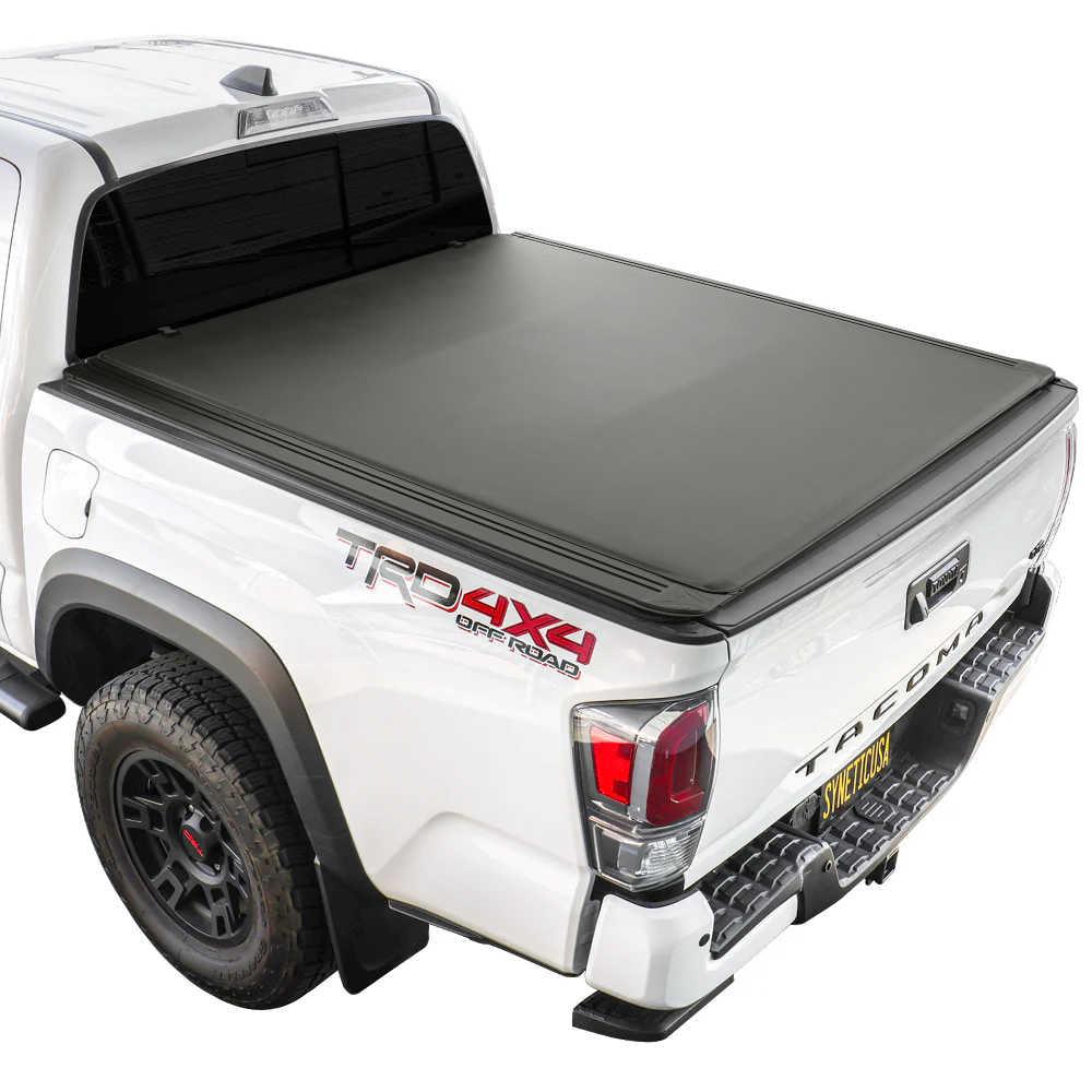 White Tacoma truck with a black soft roll up tonneau cover on a white background