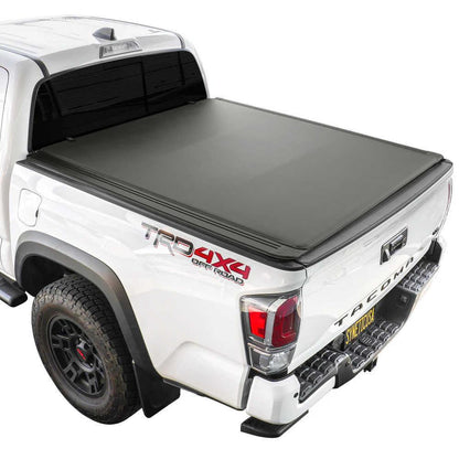 White Tacoma truck with a black soft roll up tonneau cover on a white background
