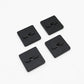Four black square molle nuts with central holes on a white background