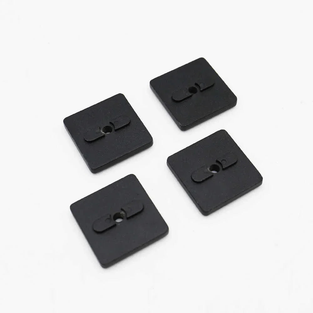 Four black square molle nuts with central holes on a white background