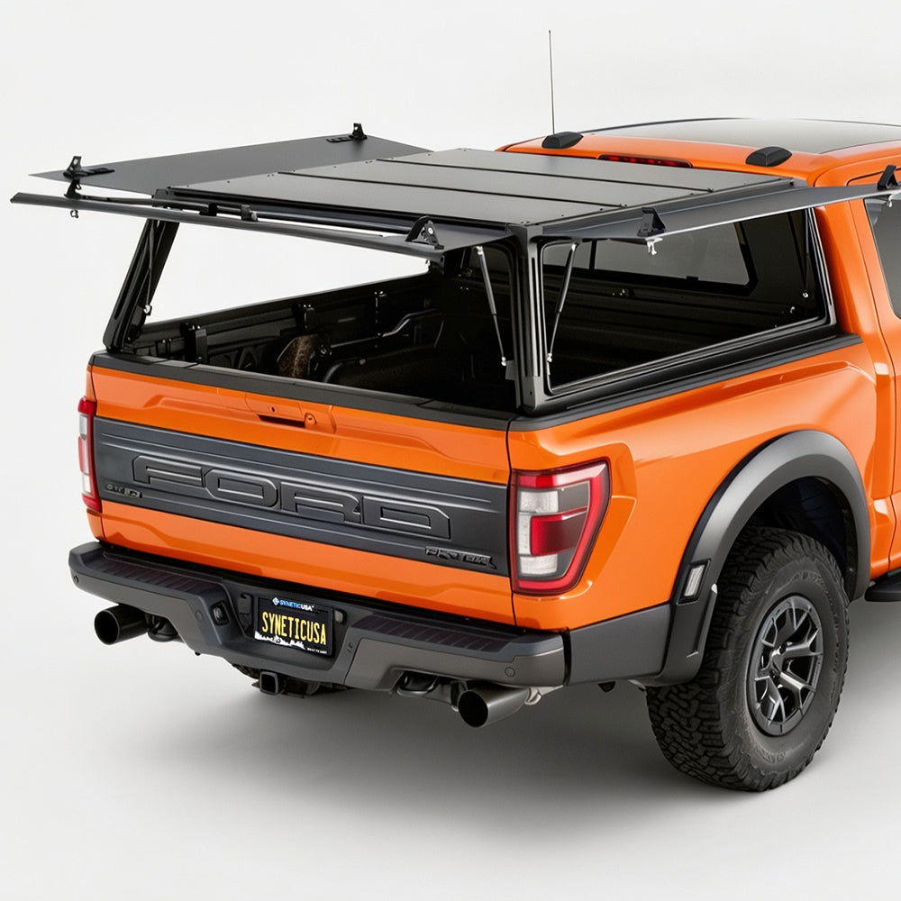An orange Ford pickup truck shown from the rear three-quarter angle with a black hardtop canopy mounted over the bed and rear window area, photographed in a clean studio setting.