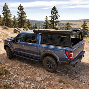 Blue pickup truck with a bed cover in a natural landscape