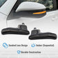 Car side mirror with smoked lens design and amber sequential indicator, accompanied by two wiper blades on a white background.