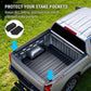 A silver pickup truck on grass showing a black protective bed liner installed in the bed, with text explaining protection for stake pockets and two inset black pad pieces highlighted by arrows.