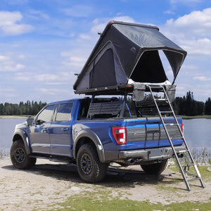 blue raptor installed syneticusa mr retractable tonneau cover and rack system with side panel and bush cruiser roof top tent