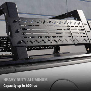Black aluminum truck bed rack mounted over the bed of a dark pickup truck, with text overlay reading 'HEAVY DUTY ALUMINUM Capacity up to 600 lbs'.