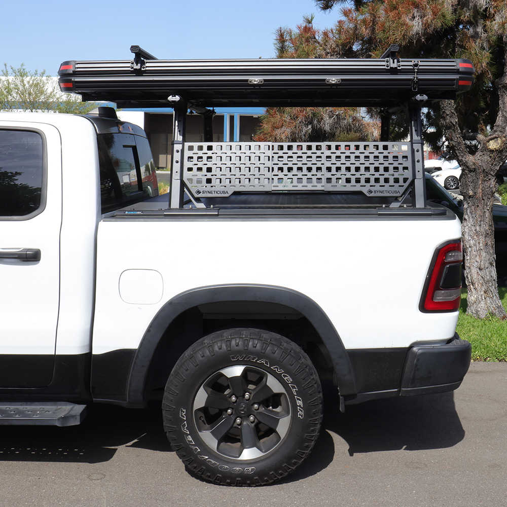White truck with syneticusa roof rack and cargo bed cover in an outdoor setting