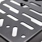 Close-up of a black metal mounting plate with elongated and circular cutouts, showing a matte textured surface.