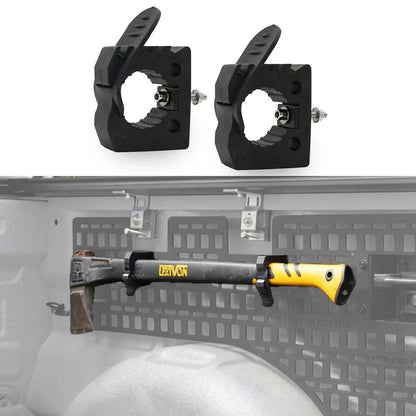 Two black plastic mounting brackets shown above, with a shotgun mounted on the inside of a vehicle tailgate below against a gray background.