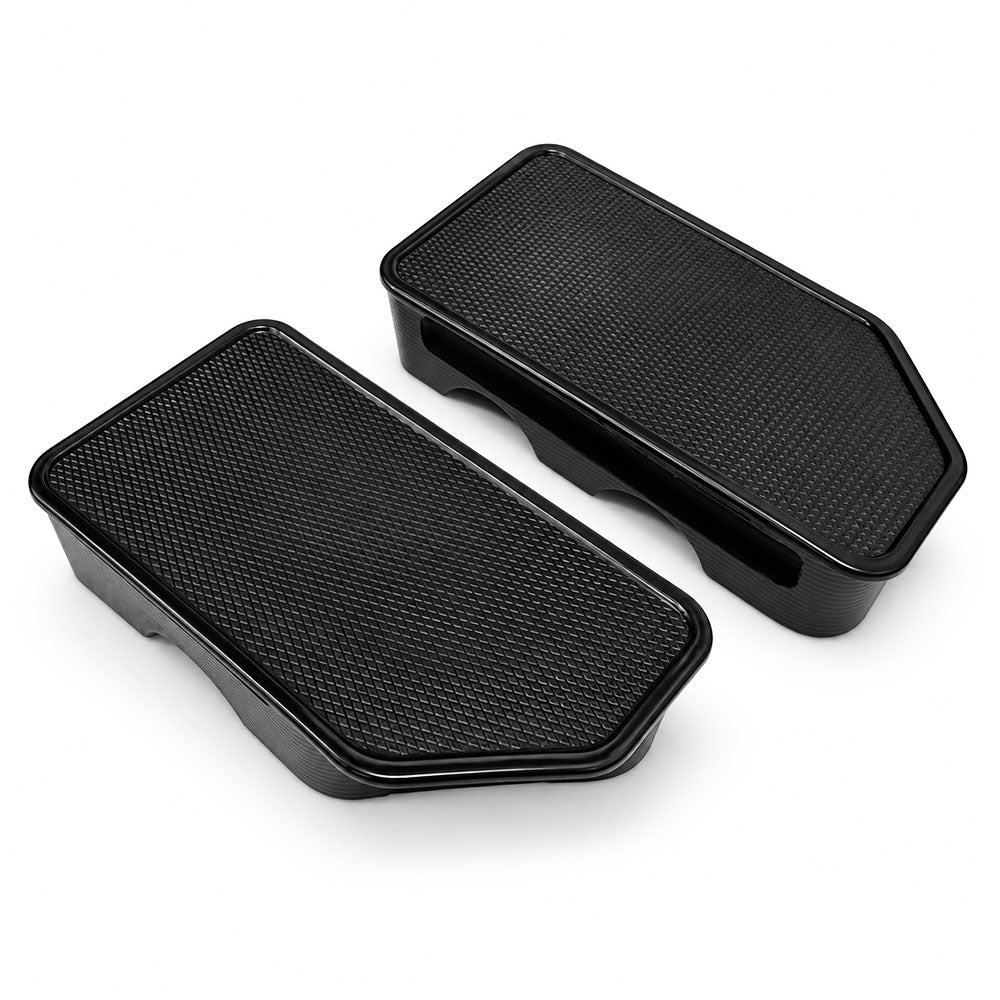 A pair of black plastic footrests with textured tops, shown on a clean white background.