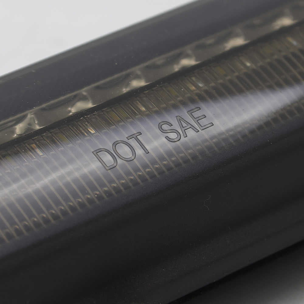 Close-up of a black metal component with 'DOT SAE' engraving on a gray background