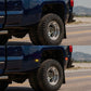 Close-up of a truck's tire on a road with mountains in the background