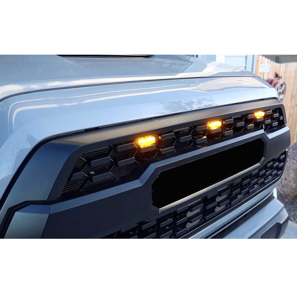 Close-up of a Tacoma's front grille with illuminated indicator lights.