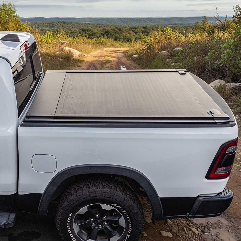 White truck with a tonneau cover on a dirt road with a scenic background