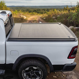 White truck with a tonneau cover on a dirt road with a scenic background