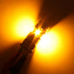 A close-up of a bright yellow automotive light bulb or LED light component with a visible connector, casting a strong warm yellow glow against a dark background.