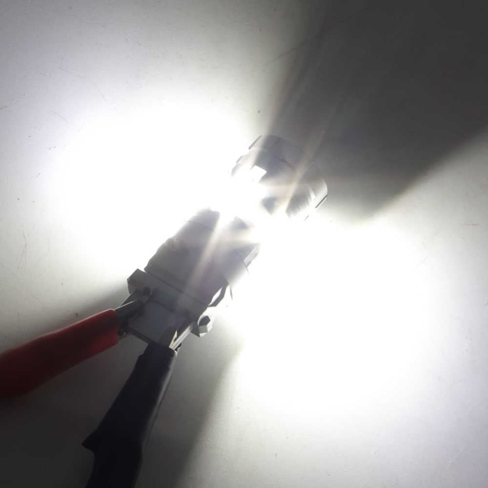 A close-up of a bright white light bulb or lamp with a red and black handle, shown against a plain white background with strong glare and lens flare.