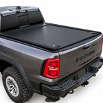 A black roll-up truck bed cover installed on the bed of a dark gray Ram pickup truck, shown from a rear three-quarter angle against a white studio background.