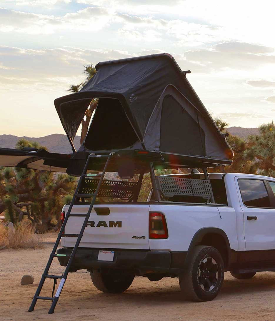 White truck with a rooftop tent in a desert setting