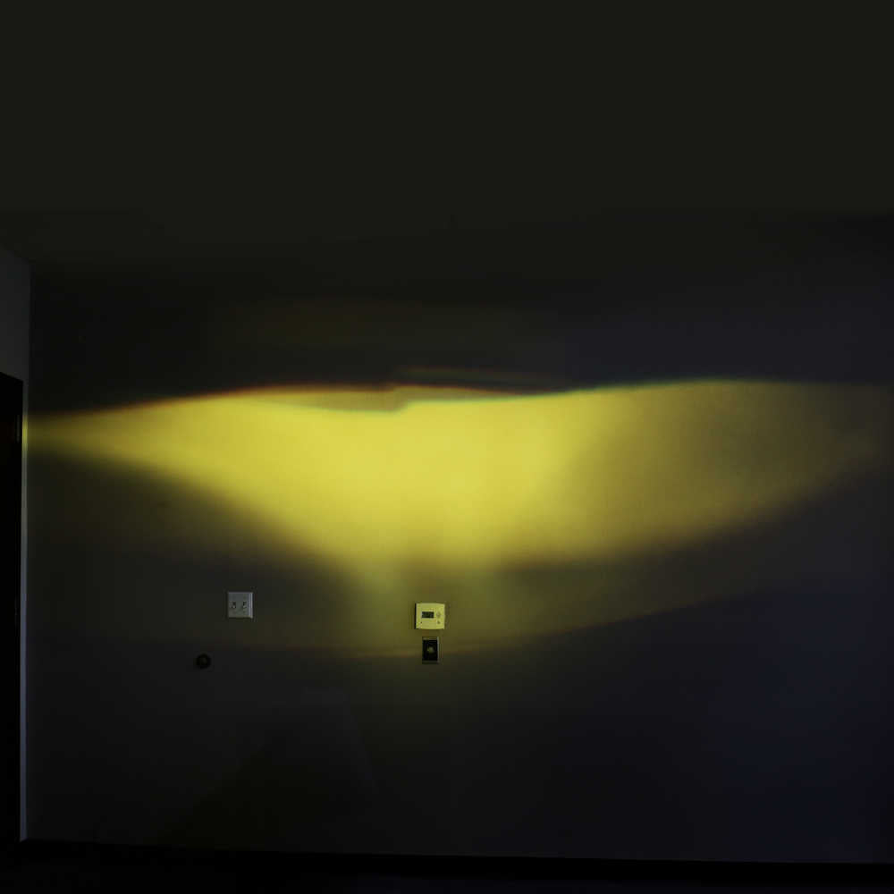 Dark room with a light source casting a yellow glow on the wall.