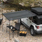 White SUV with a rooftop tent and outdoor furniture near a rocky stream.