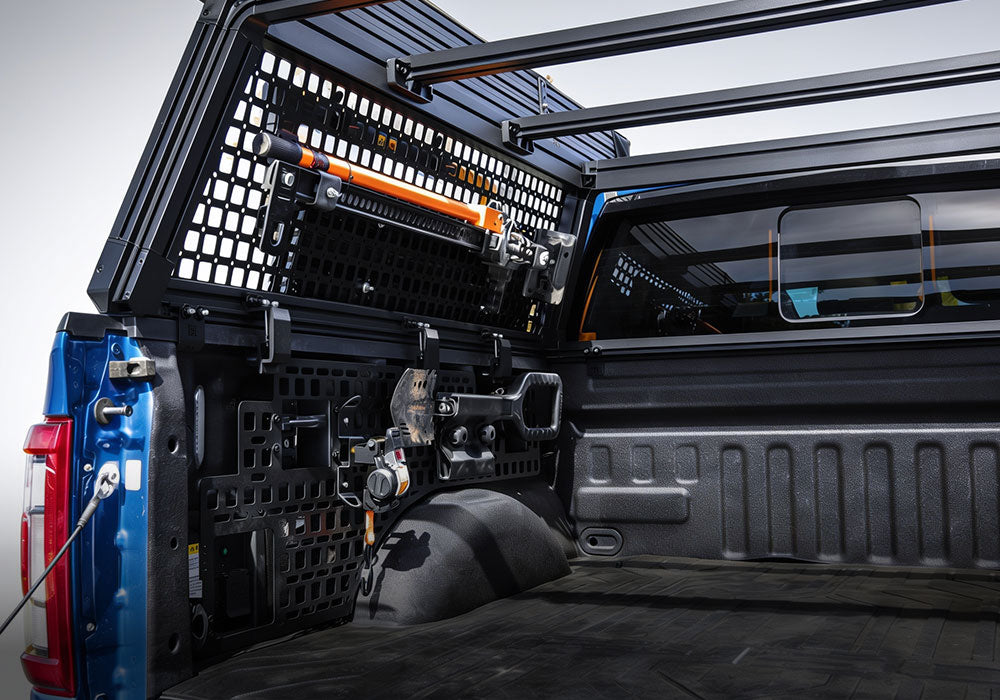 Black metal truck bed rack system installed on the bed of a blue pickup truck, featuring a canopy frame, roof rack, and cargo management accessories.