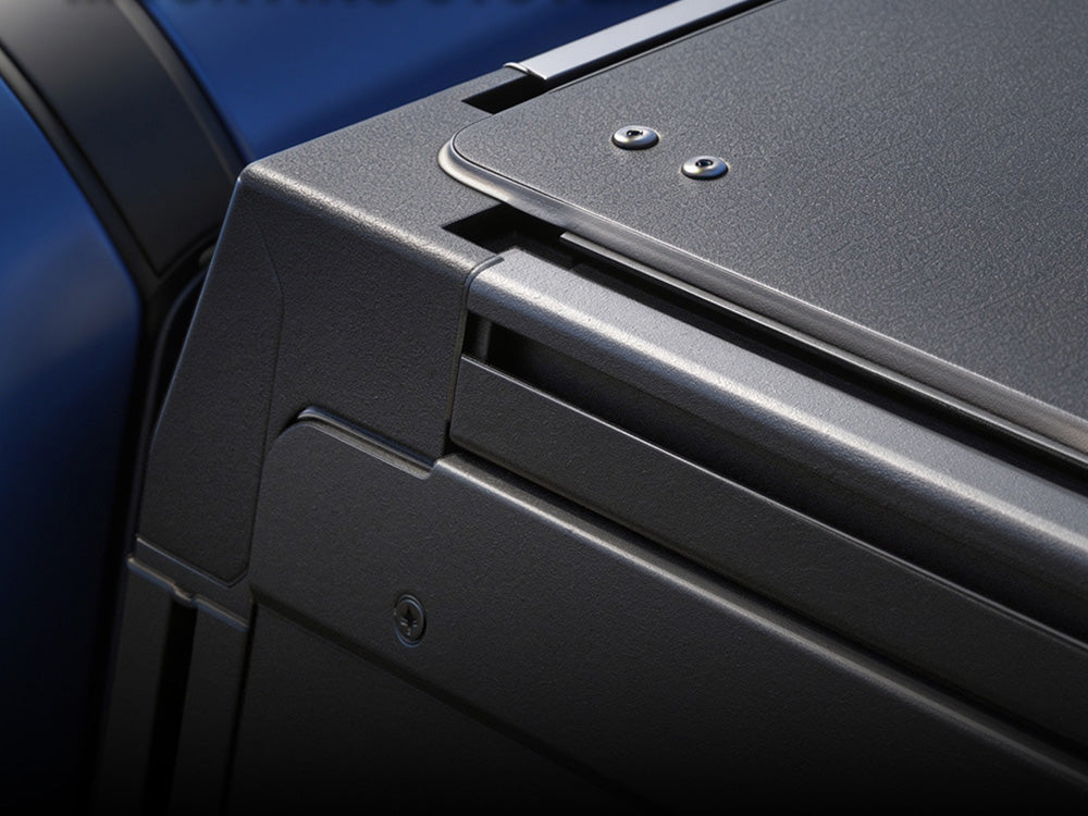 Close-up detail of a dark gray textured metal panel with screws and a horizontal metallic trim, set against a blue background.