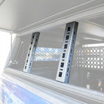 Two tall rectangular matte black brackets installed vertically on the inside of a vehicle window or canopy frame.