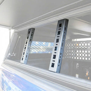Two tall rectangular matte black brackets installed vertically on the inside of a vehicle window or canopy frame.