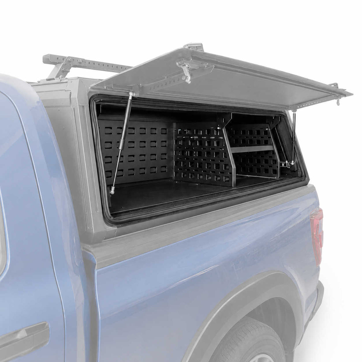 A black hardtop utility canopy mounted on the bed of a light blue pickup truck, shown with the shell open to reveal storage compartments and side racks against a white background.