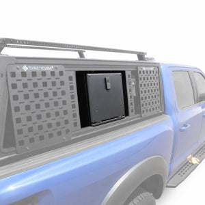A blue pickup truck with a gray SYNETICUSA modular cap and storage compartment system, shown on a clean white background.