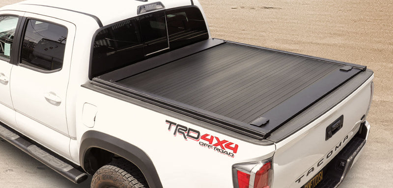 White Toyota Tacoma truck with a black tonneau cover on a beige background