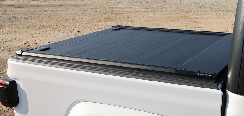 Retractable truck bed cover on a white truck against a desert background