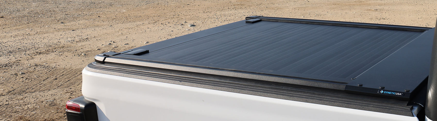 Black truck bed cover on a white truck against a desert background
