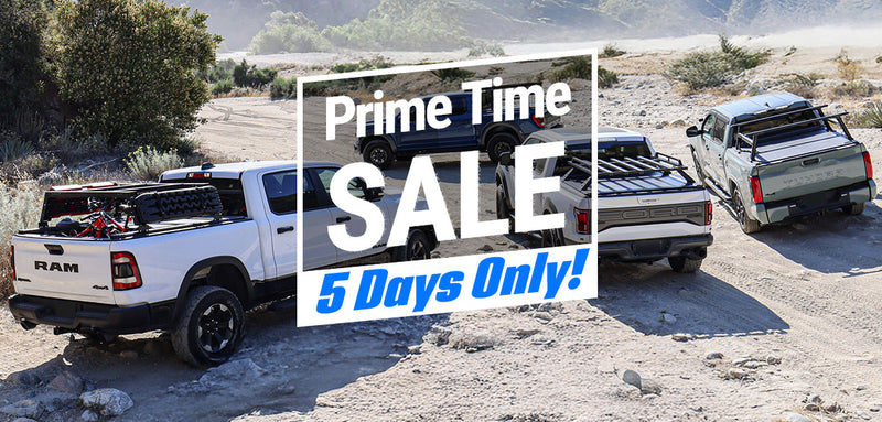Three pickup trucks with cargo racks in a desert setting, featuring a 'Prime Time Sale' banner.