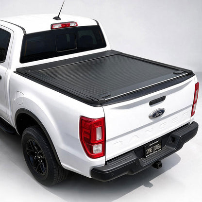 A black roll-up truck bed cover installed on the bed of a white Ford Ranger pickup truck, shown from a rear three-quarter angle on a light gray studio background.