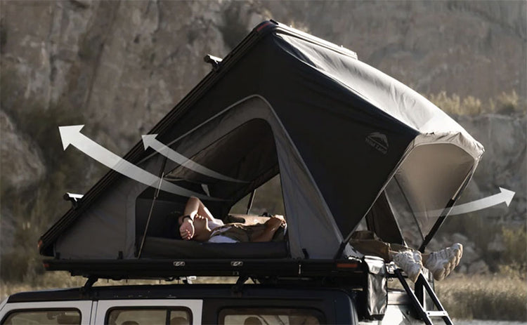 Person lying on a rooftop tent with a scenic background