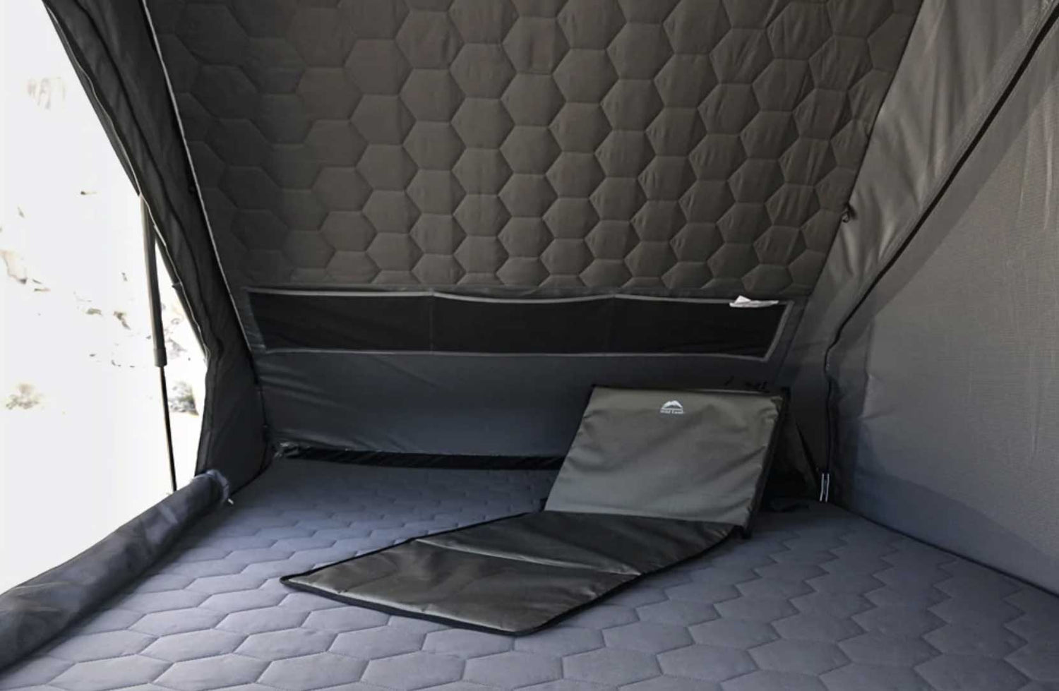 Gray quilted interior of a camping tent with a green lounge