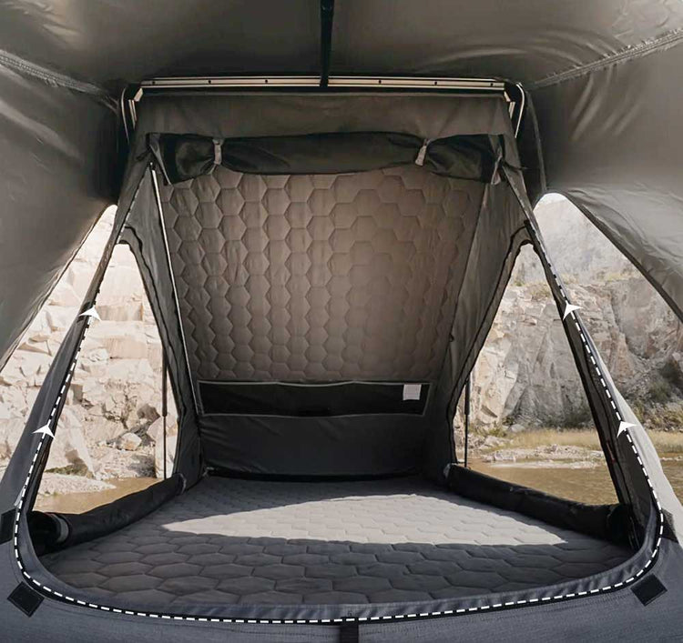 Camping pod with quilted interior and quilted floor, set against a natural landscape.
